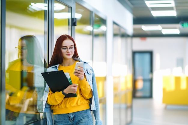 Bella donna che utilizza il telefono in un moderno edificio per uffici Giovane ragazza freelance che lavora in ufficio