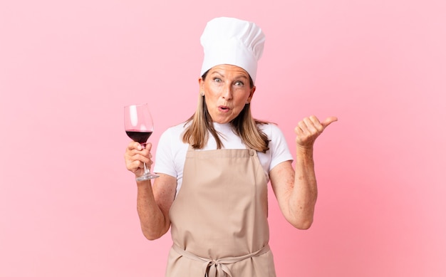 Bella donna chef di mezza età con un bicchiere di vino