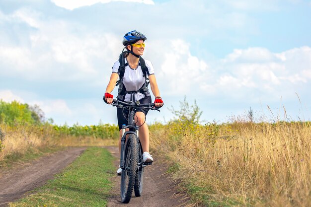 Bella donna ciclista cavalca sul campo in bicicletta