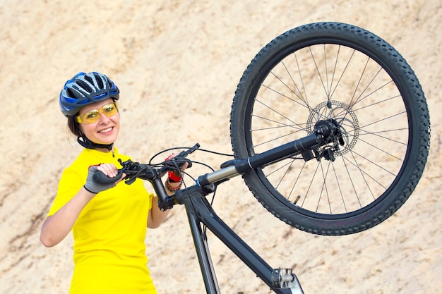 Bella donna ciclista con bici sullo sfondo delle sabbie. sport e ricreazione. Natura e uomo