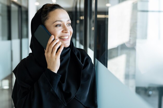 Bella donna con abito abaya che lavora e stampa documenti. Impiegata di mezza età al lavoro in un ufficio commerciale a Dubai. Concetto di culture e stile di vita mediorientali