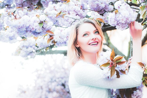 Bella donna con albero di sakura in fiore e giornata di sole