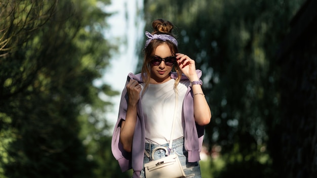 Bella donna con bandana alla moda e occhiali da sole eleganti in abiti sportivi casual passeggiate nel parco