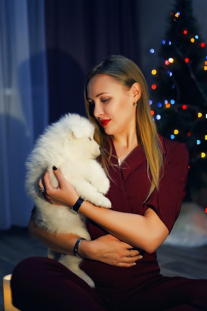 Bella donna con cane husky samoiedo in decorazioni natalizie