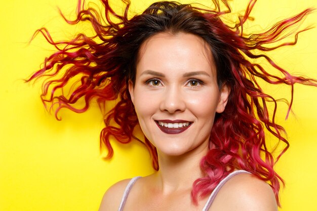 Bella donna con capelli rossi ondulati su sfondo giallo