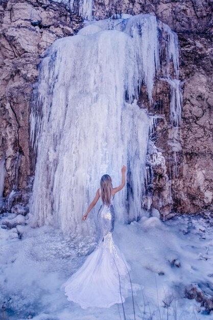 Bella donna con cascata di ghiaccio in inverno