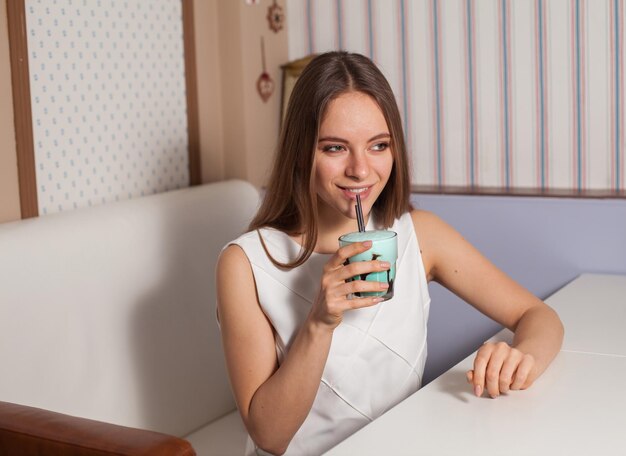 Bella donna con cocktail in un caffè moderno