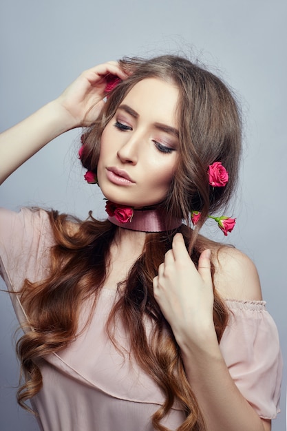 Bella donna con fiori di rosa tra i capelli lunghi