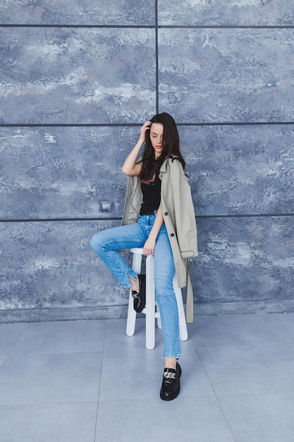 Bella donna con gambe snelle in jeans e capispalla alla moda con un impermeabile scarpe in pelle alla moda Immagine femminile in stile primaverile