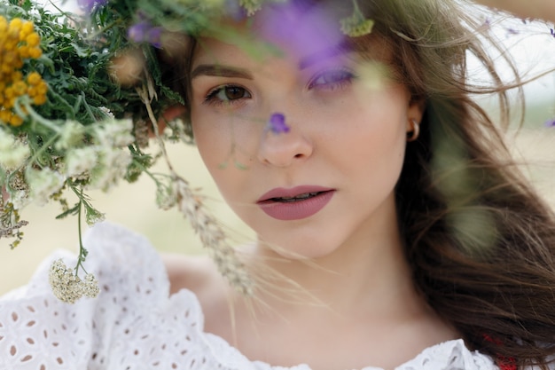 Bella donna con ghirlanda di fiori sulla testa. Ragazza di bellezza con l'acconciatura di fiori. Ragazza in una foresta estiva. Foto di moda