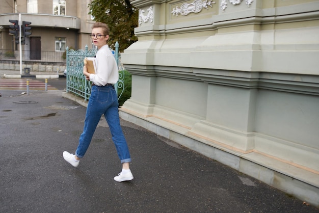Bella donna con i capelli corti sta camminando per strada con un libro in mano