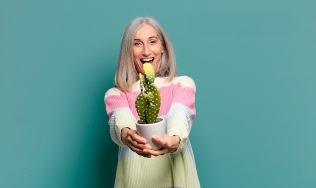 Bella donna con i capelli grigi con un cactus