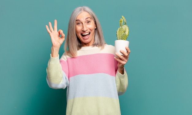 Bella donna con i capelli grigi con un cactus