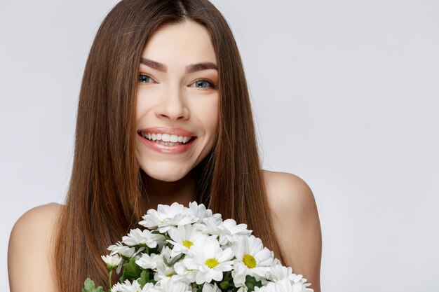 Bella donna con i fiori puliti della holding della pelle fresca