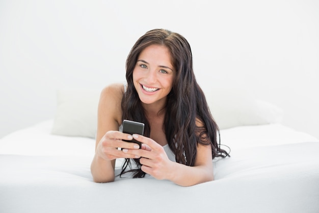 Bella donna con il cellulare a letto