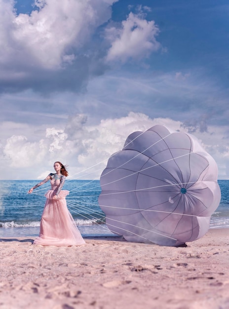 Bella donna con il paracadute bianco in spiaggia