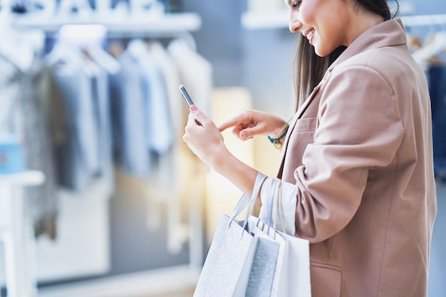 Bella donna con il telefono in un negozio di vestiti. Foto di alta qualità