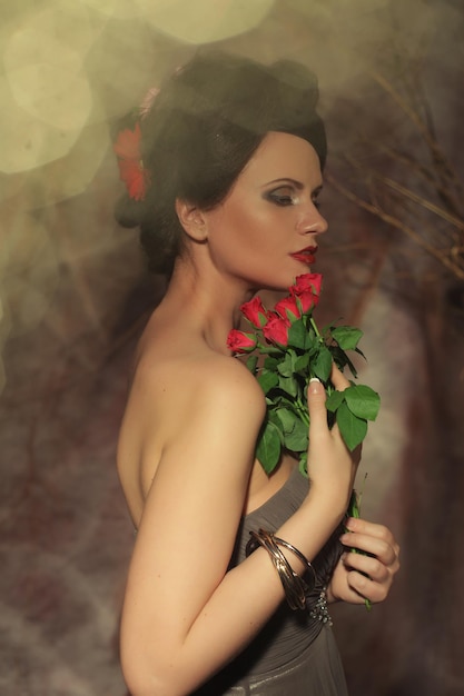 Bella donna con l'immagine di moda di rose rosse