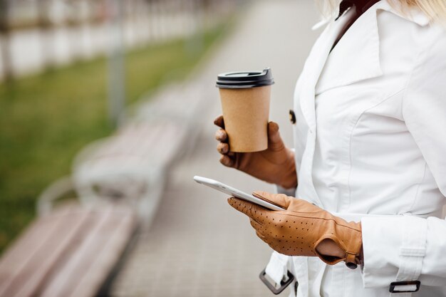 Bella donna con la tazza di caffè vicino all'edificio per uffici.