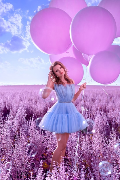 Bella donna con palloncini rosa nel campo di lavanda