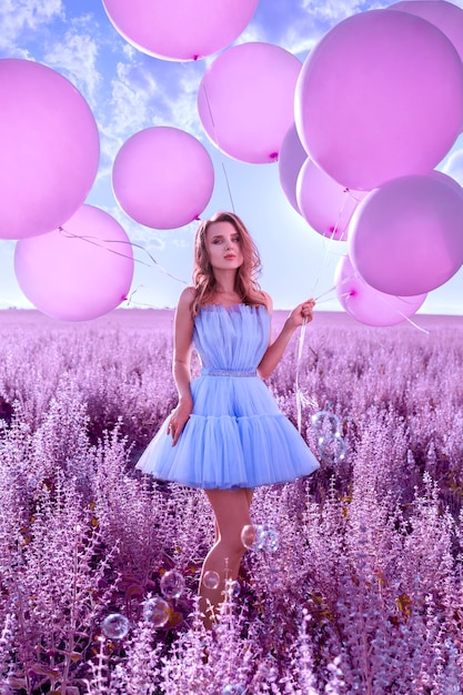 Bella donna con palloncini rosa nel campo di lavanda