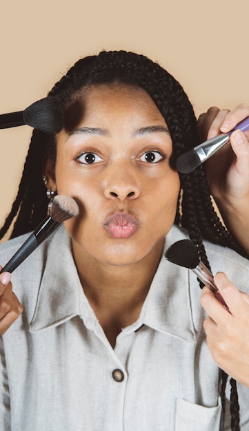 Bella donna con pennelli per il trucco sul viso, bellezza, modella formosa