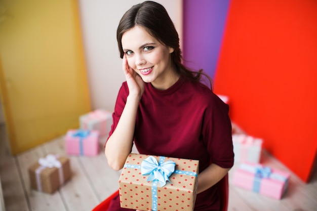 Bella donna con regalo su sfondo colorato.