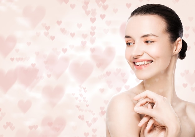 Bella donna con sorriso carino trucco naturale spa cura della pelle ritratto rosa bokeh cuore amore sfondo bianco