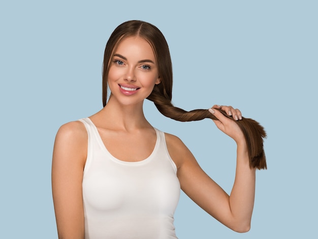 Bella donna con stile casuale di bellezza della coda dei capelli sani lunghi lisci. Colore di sfondo blu