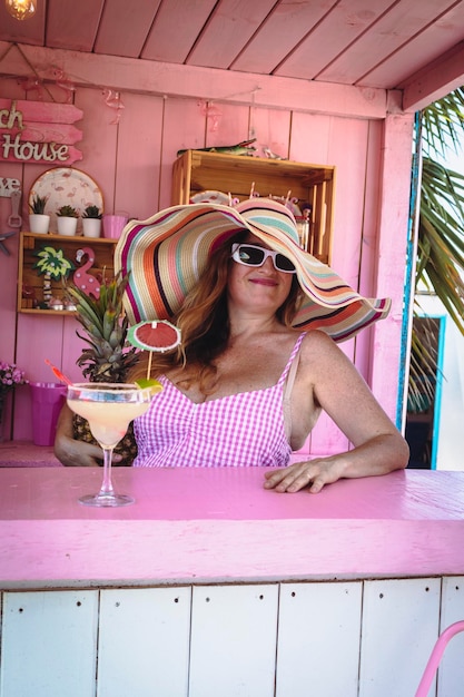 Bella donna con un cappello che beve un margarita. Momenti di relax in spiaggia o in piscina.