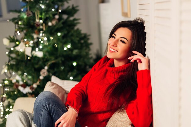 Bella donna con un maglione rosso sul divano