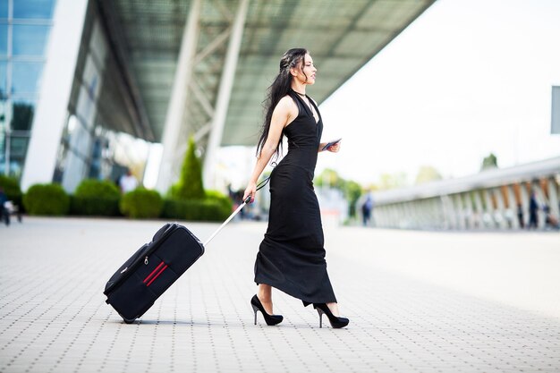 Bella donna con una valigia vicino all'aeroporto.