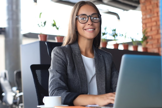 Bella donna d'affari che lavora al computer portatile in ufficio.