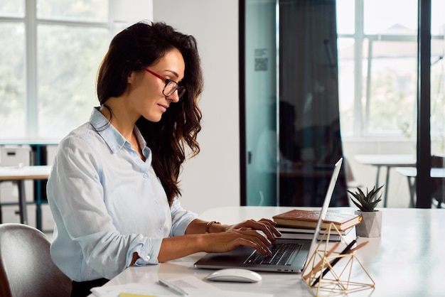 Bella donna d'affari che lavora su un computer portatile in ufficio