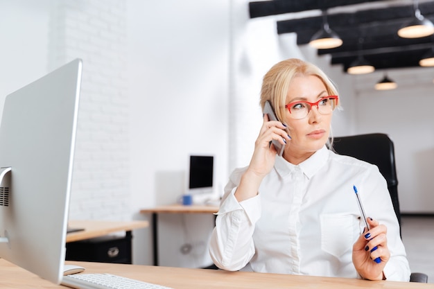 Bella donna d'affari maturi parlando al telefono in ufficio