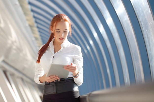 Bella donna d'affari moderna utilizzando computer tablet all'interno di un edificio moderno