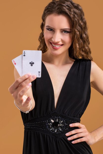Bella donna dai capelli castani che tiene due assi come segno per il gioco del poker, il gioco d'azzardo e il casinò