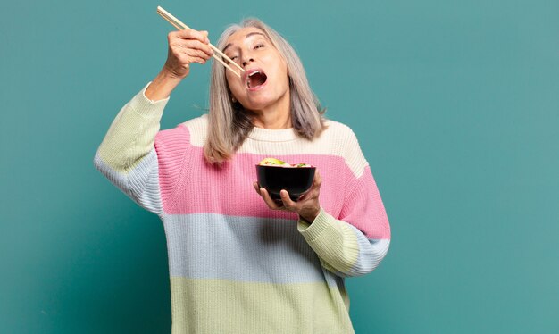 Bella donna dai capelli grigi con una ciotola di ramen