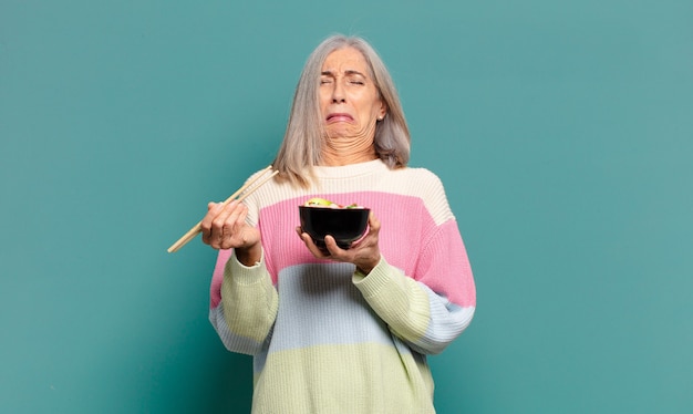 Bella donna dai capelli grigi con una ciotola di ramen