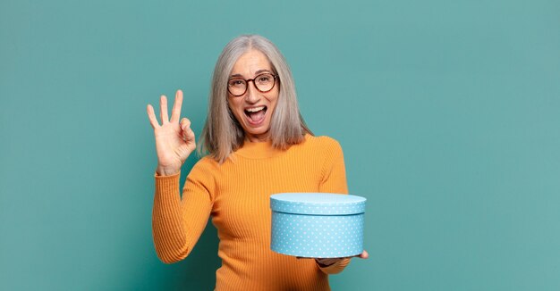 Bella donna dai capelli grigi con una confezione regalo