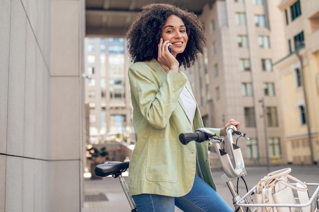 Bella donna dai capelli ricci con una bicicletta in strada