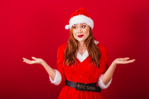 Bella donna dai capelli rossi brasiliana vestita di abiti natalizi Babbo Natale espressione di dubbio