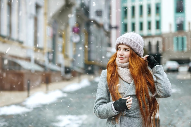 Bella donna dai capelli rossi che cammina per strada durante le vacanze di Natale. Spazio per il testo