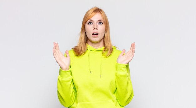 Bella donna dai capelli rossi che sembra scioccata e stupita, con la bocca aperta per la sorpresa quando si rende conto di qualcosa di incredibile