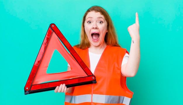 Bella donna dai capelli rossi che si sente come un genio felice ed eccitato dopo aver realizzato un'idea di un incidente a un triangolo automobilistico