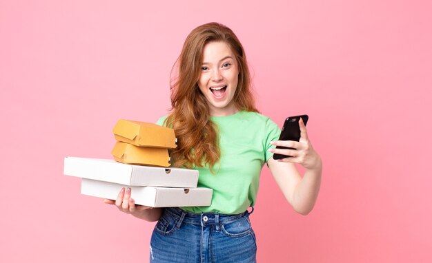 Bella donna dai capelli rossi che tiene in mano scatole di fast food da asporto?