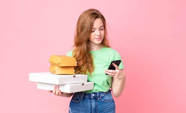 Bella donna dai capelli rossi che tiene in mano scatole di fast food da asporto?