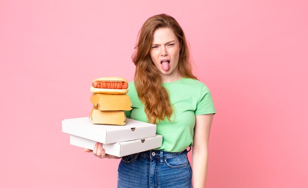 Bella donna dai capelli rossi che tiene in mano scatole di fast food da asporto?