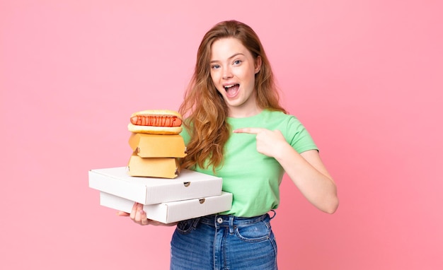 Bella donna dai capelli rossi che tiene in mano scatole di fast food da asporto?