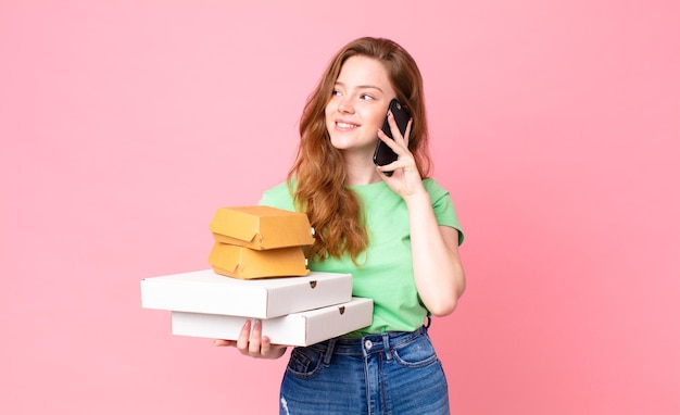 Bella donna dai capelli rossi che tiene in mano scatole di fast food da asporto?